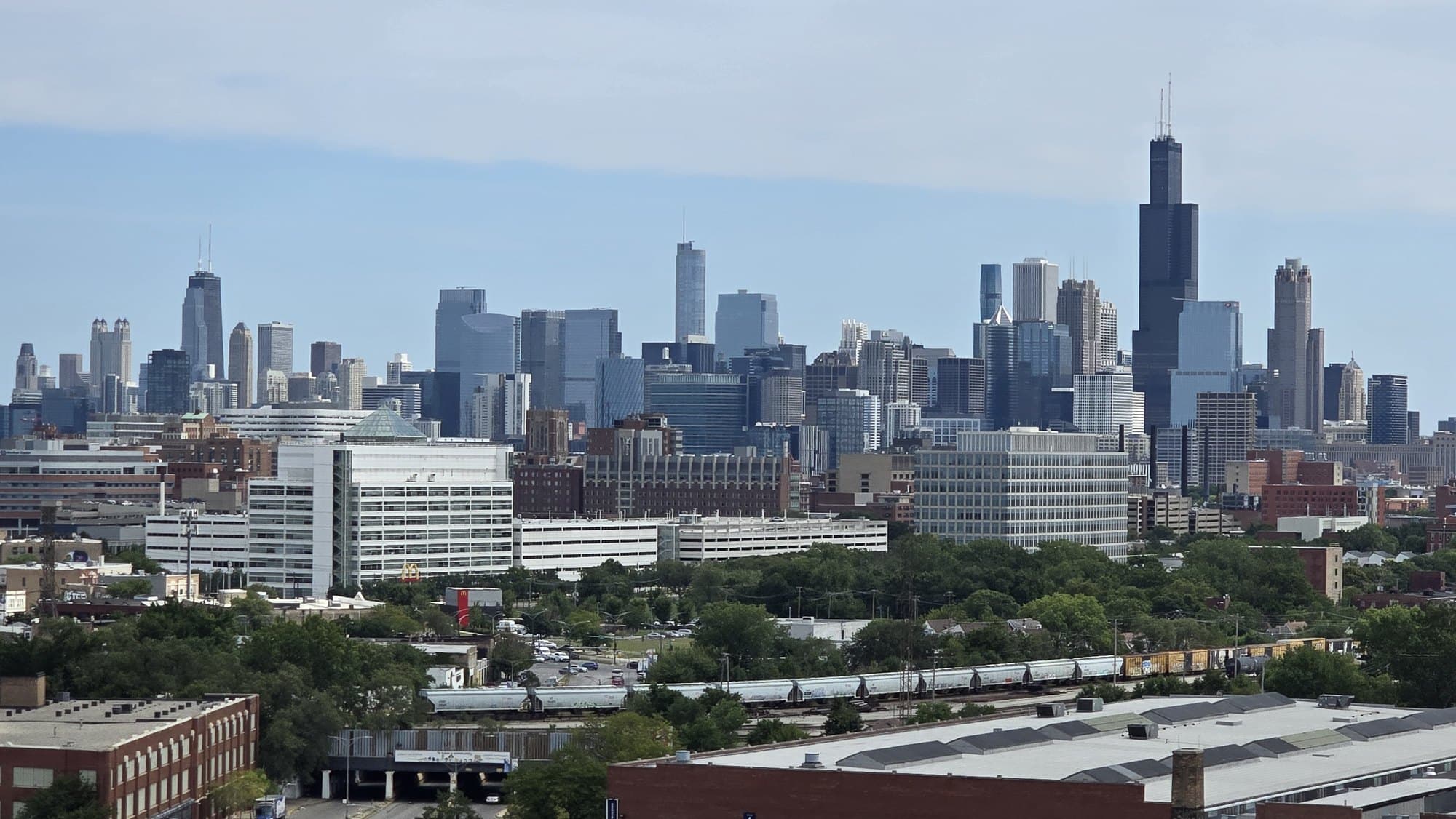 Chicago skyline featuring the Willis Tower and a long freight train in the foreground.