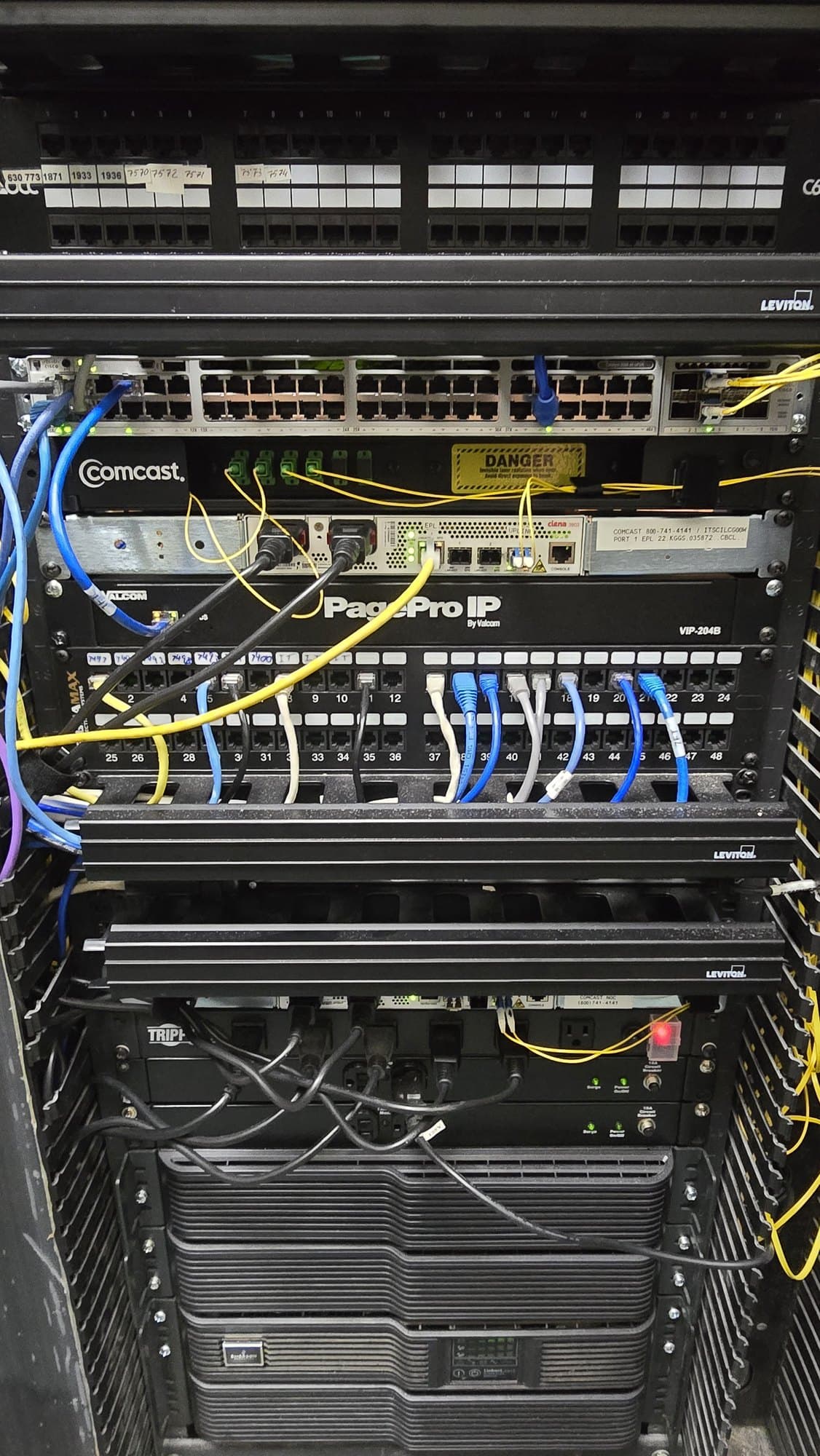 Server rack containing networking switches, patch panels, and a complex web of colorful cables.